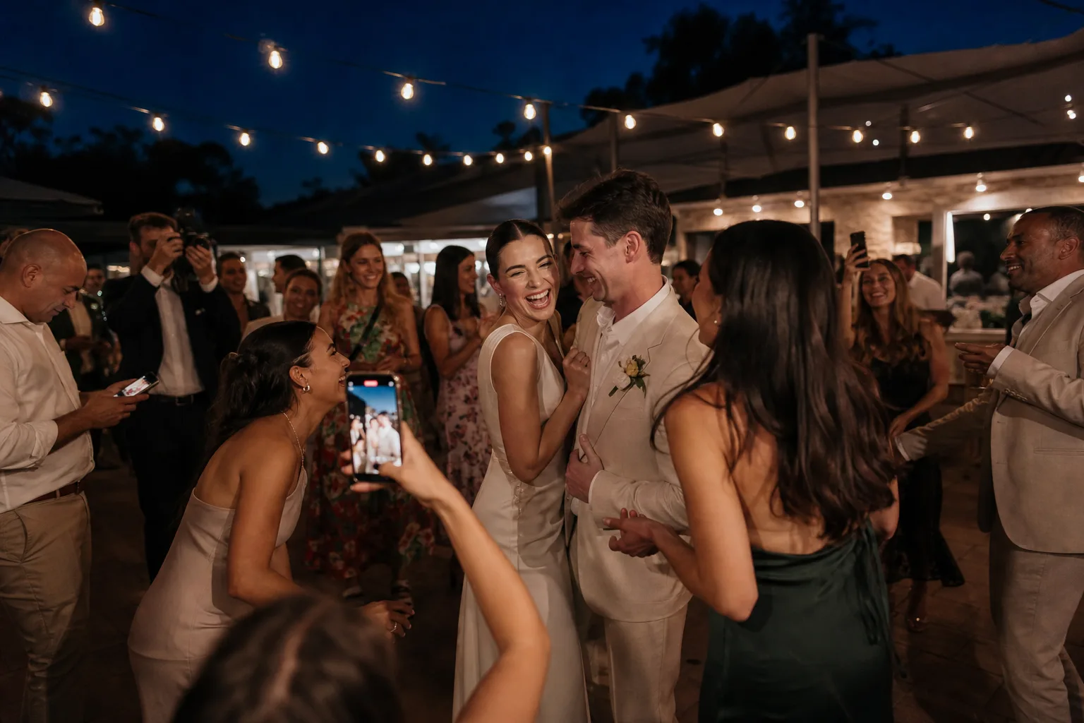 Friends photographing a newly married couple from around the dance floor